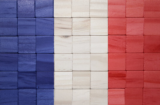 colorful painted big national flag of france on a wooden cubes texture.