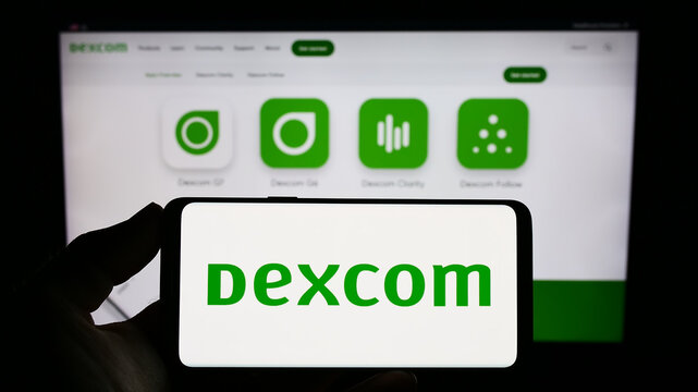 Stuttgart, Germany - 06-28-2023: Person holding smartphone with logo of US medical technology company DexCom Inc. on screen in front of website. Focus on phone display.
