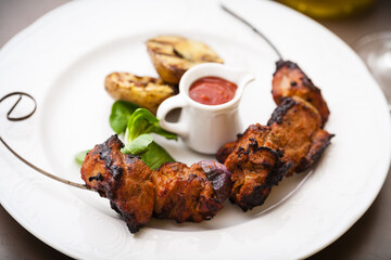 Pork shashlik with grilled potatoes served on a white plate