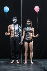 Nice couple of pole dancers holds their hands together next to a pylon on a dark background in the...