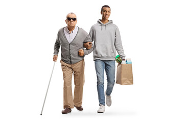 Young african american man with grocery bags walking with an elderly blind man