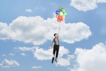 Mime flying and holding a bunch of balloons up in the sky