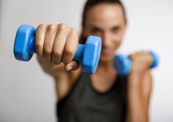 Young fitness woman making exercises with dumbbells