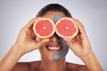 Hands with grapefruit, skincare and face mask with clay, charcoal or natural beauty product for wellness, detox or nutrition. Fruit, woman in funny pose and healthy cosmetics for facial care