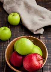 Green and red organic  apples in bowl on wooden board. Healthy food