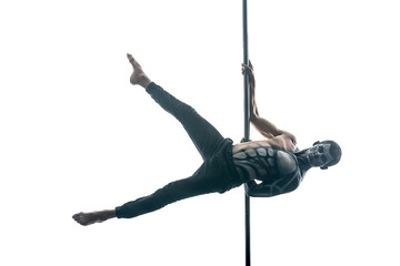 Athletic pole dancer with horrific body-art hangs horizontal on a pylon in the studio on the white background. He wears black pants and looks into the camera. His legs are outstretched to the sides.