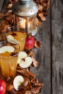 Hot apple cider with cinnamon sticks and spices on fall leaves background