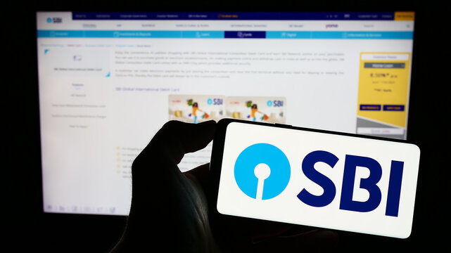 Stuttgart, Germany - 06-30-2023: Person holding cellphone with logo of Indian company State Bank of India (SBI) on screen in front of business webpage. Focus on phone display.
