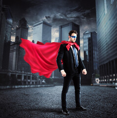 Businessman with a superhero cape and mask lands on the asphalt of a city street © Designpics
