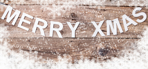 Merry Christmas sign with snow on wooden background with copy space