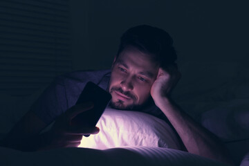 Man using smartphone in bed at night. Internet addiction