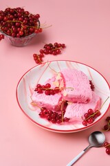 Summer refreshing dessert, sliced Italian semifreddo ice cream with red currants in a red and white plate on a pink plain background. Ice cream recipes.