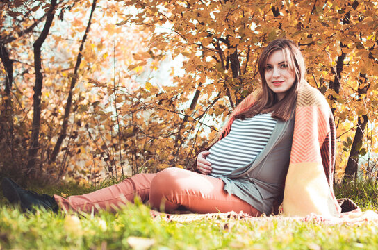 Young pregnant woman with a big belly on outdoors