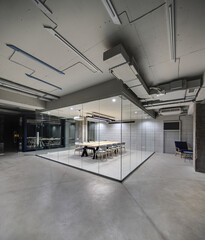 Office in a loft style with glowing lamps, light brick walls and concrete columns. There is a...