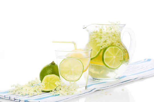 Elderberry lemonade with fresh lemon and lime and elderberry blossom isolated on white background. Fresh summer healthy drink.