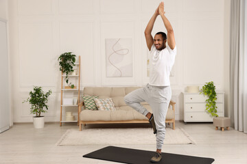 Man doing morning exercise on fitness mat at home - Powered by Adobe