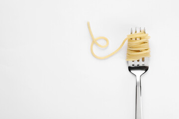 Fork with tasty pasta on white background, top view. Space for text