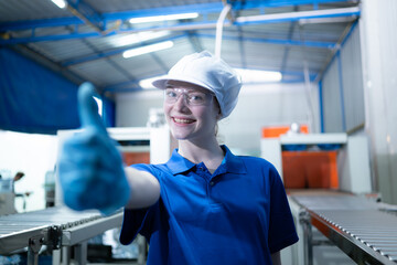Portrait of happy female factory worker showing thumbs up gesture in drinking water factory