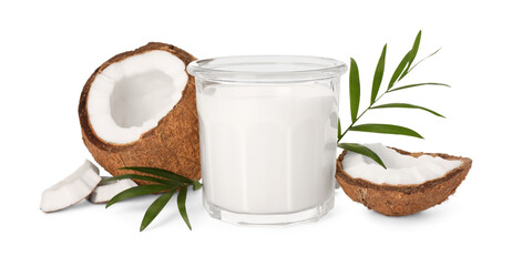 Glass of delicious vegan milk, coconut pieces and green leaves on white background