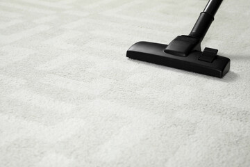 Hoovering white carpet with modern vacuum cleaner. Space for text