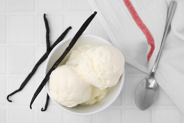 Delicious ice cream, spoon and vanilla pods on white tiled table, flat lay