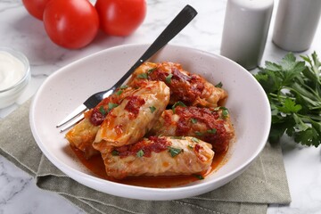 Delicious stuffed cabbage rolls cooked with homemade tomato sauce on white marble table, closeup