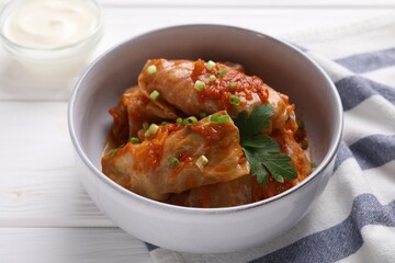Delicious stuffed cabbage rolls cooked with homemade tomato sauce on white wooden table, closeup