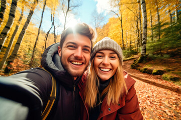 Attractive couple taking a selfie in a forest in autumn - obrazy, fototapety, plakaty