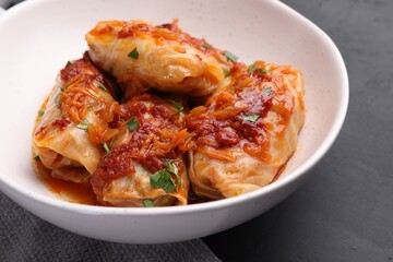 Delicious stuffed cabbage rolls cooked with homemade tomato sauce on black table, closeup