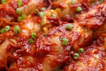 Delicious stuffed cabbage rolls cooked with homemade tomato sauce as background, closeup