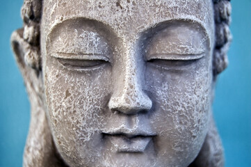 Fototapeta na wymiar Buddha face on blue background. Close up. Symbol of Buddhism religion
