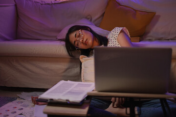 Young Female worker or freelancer is sleeping while working deadline project at night. Woman taking a nap or break while working. Overload or overtime job. Workaholic, Head down in front of laptop.