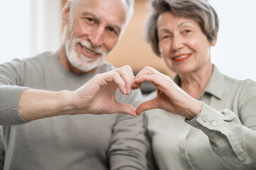 Mature couple showing heart gesture make love sign with hands