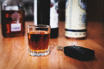 Drunk driving.Drink and auto keys.A glass of whiskey and car keys on the table.To drive or not to drive, alcohol addiction concept. - obrazy, fototapety, plakaty