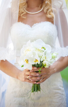 Cropped view of elegant bride holding flowers outdoors