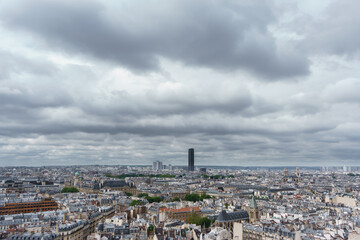 Fototapeta na wymiar Cloudy day with Montparnasse tower over Paris roofs skyline