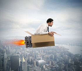 Businessman flying with a cardboard missile with fire in the sky