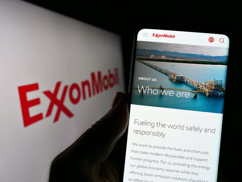 Stuttgart, Germany - 07-01-2023: Person holding cellphone with webpage of US petroleum company Exxon Mobil Corporation on screen with logo. Focus on center of phone display.