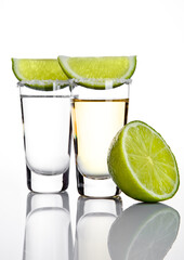 Silver tequila shot glass with lime slice and salt on white background