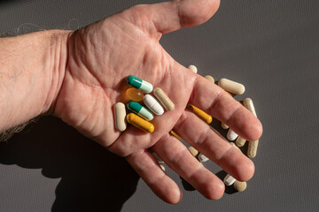 medicines, many pills put together, every day we take a lot of drugs and supplements, sometimes abusing these substances. hand holding many different pills.