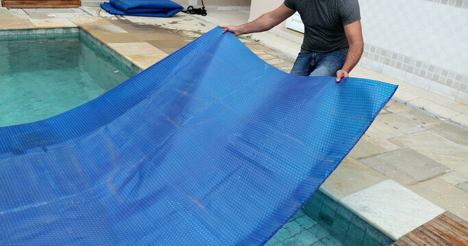 Man removing swimming pool cover and folding protector