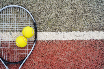 Closeup top view on yellow tennis balls and racket racquet lying on acrylic tennis hard court surface with empty blank copy space.