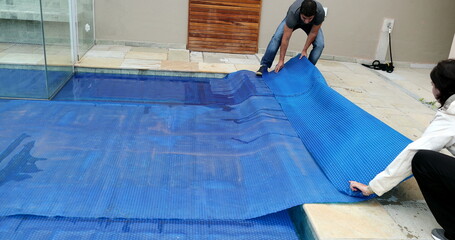 People removing swimming pool cover