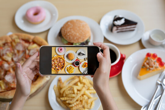restaurant owner takes a picture of the food on the table with a smartphone to post on a website. Online food delivery, ordering service, influencer, review, social media, share, marketing, interest