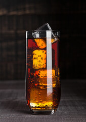 Glass of cola soda with ice cubes on wooden board background