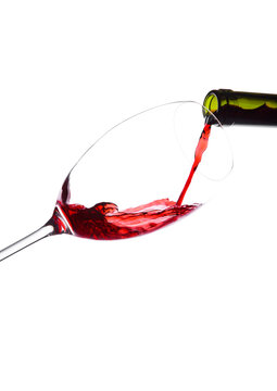 Pouring red wine from bottle to glass isolated on white background