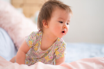 lifestyle home portrait of happy and adorable 9 months old mixed ethnicity Asian Caucasian baby girl playing cheerful and carefree on bed looking sweet and cute in childhood concept