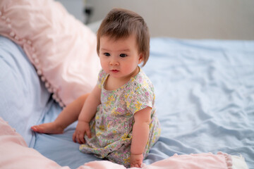 lifestyle home portrait of happy and adorable 9 months old mixed ethnicity Asian Caucasian baby girl playing cheerful and carefree on bed looking sweet and cute in childhood concept