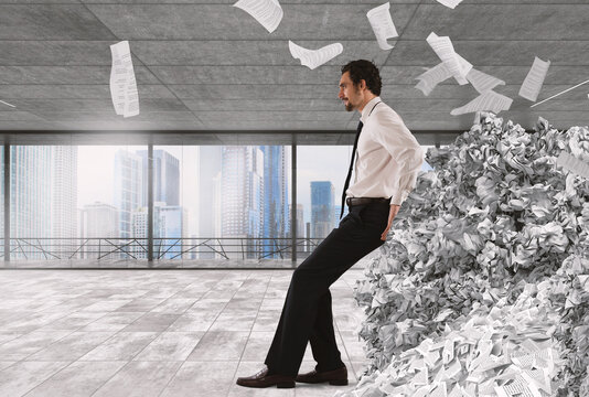 Businessman pushing with fatigue a big pile of paperwork