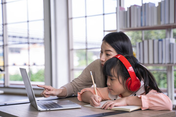 Home schooling learning at home. asian woman with her daughter in the living room